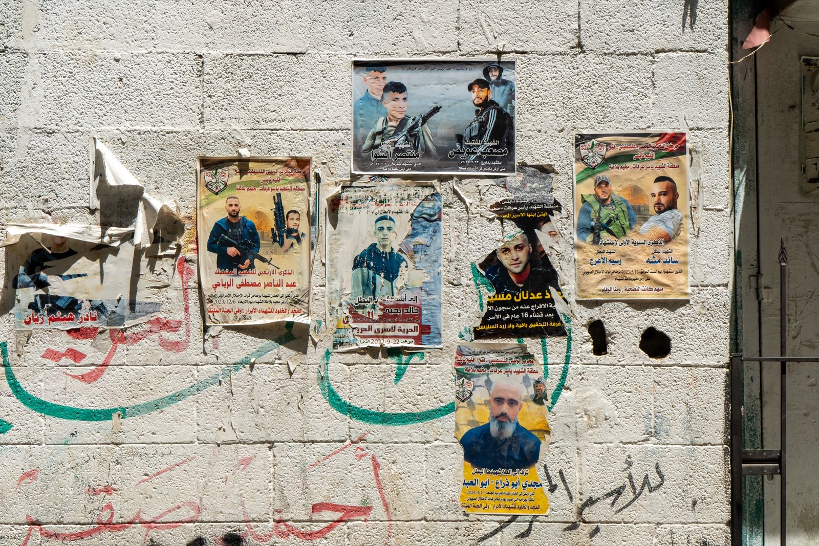Weathered political posters pasted across a concrete wall
