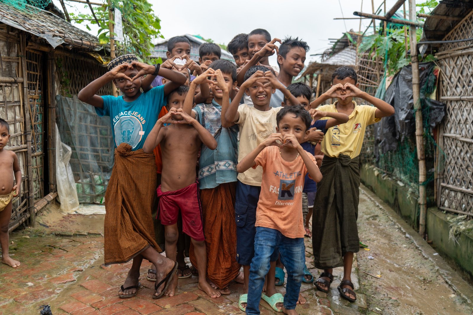 Children in a refugee settlement forming hearts with their hands