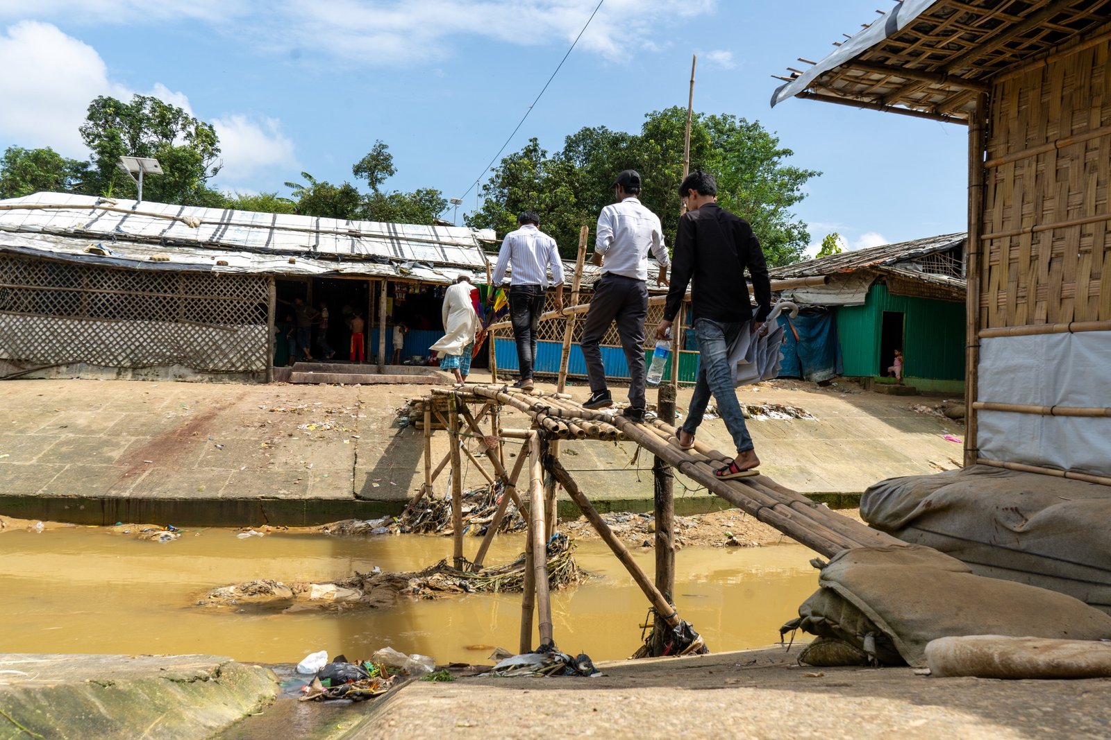 People moving carefully across a narrow bridge above water