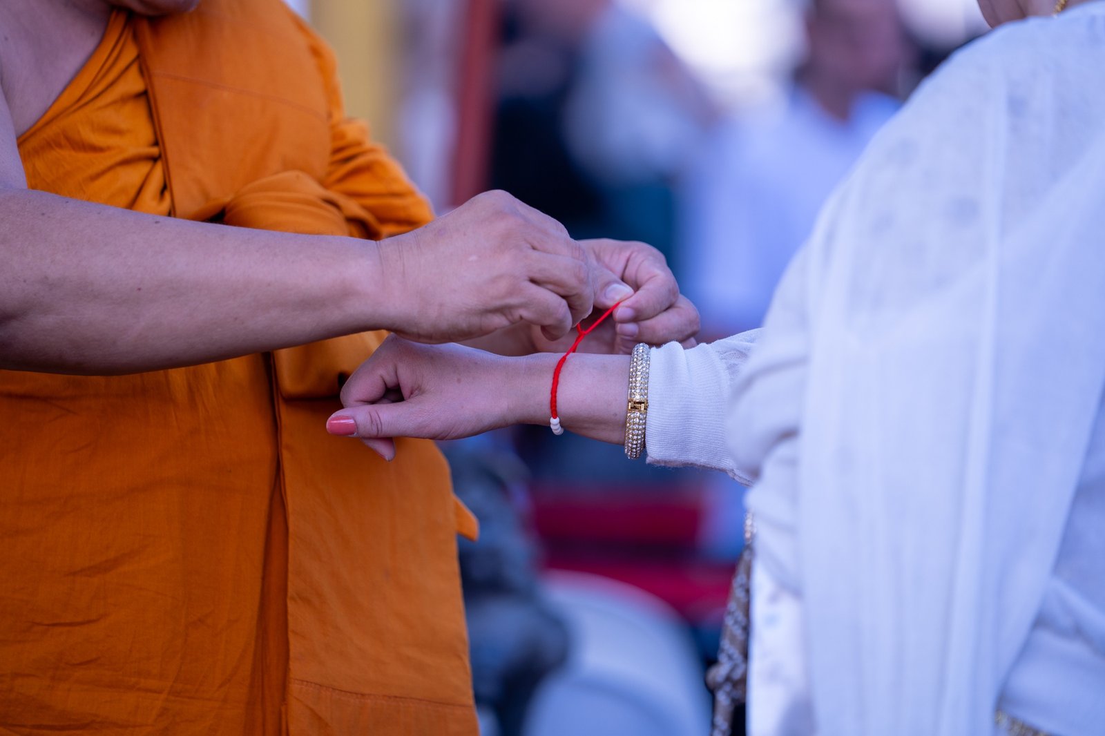 Hands tying a red thread during a ceremony