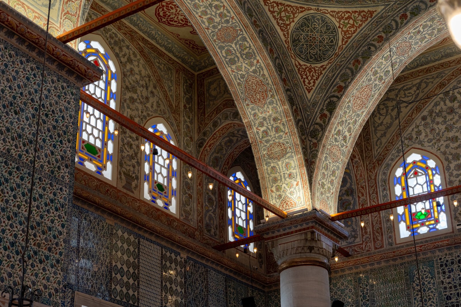 Ornate interior arches and stained glass above patterned tile walls