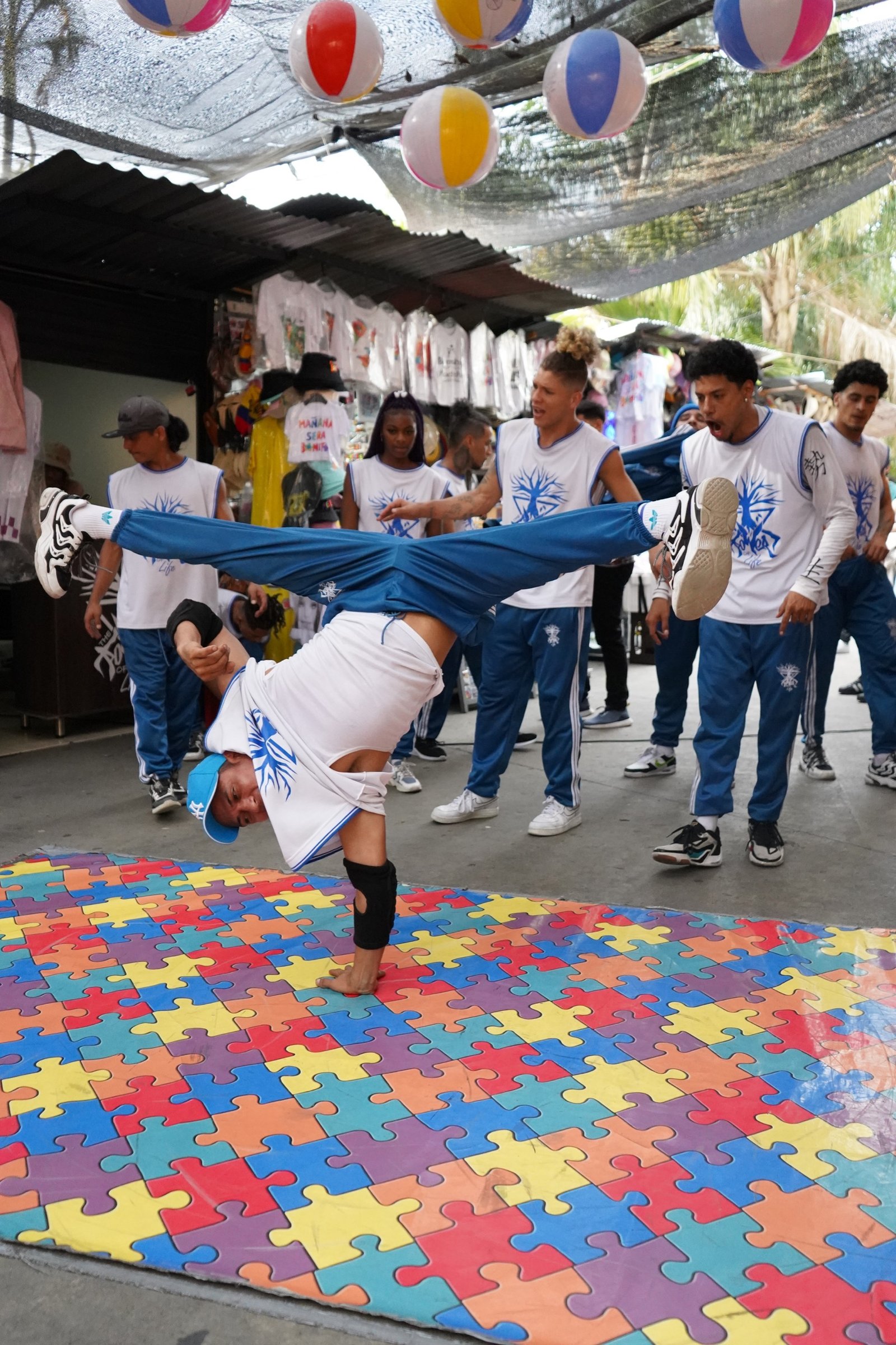 Street performer balancing during a crowd performance on a colorful mat