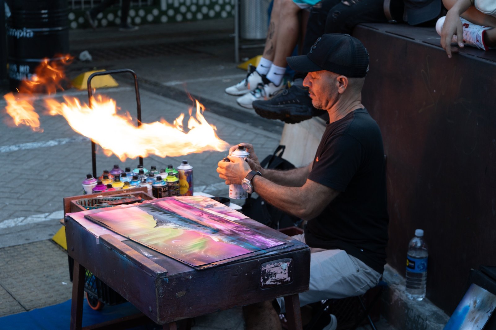 Street artist sending fire across a painted surface at night