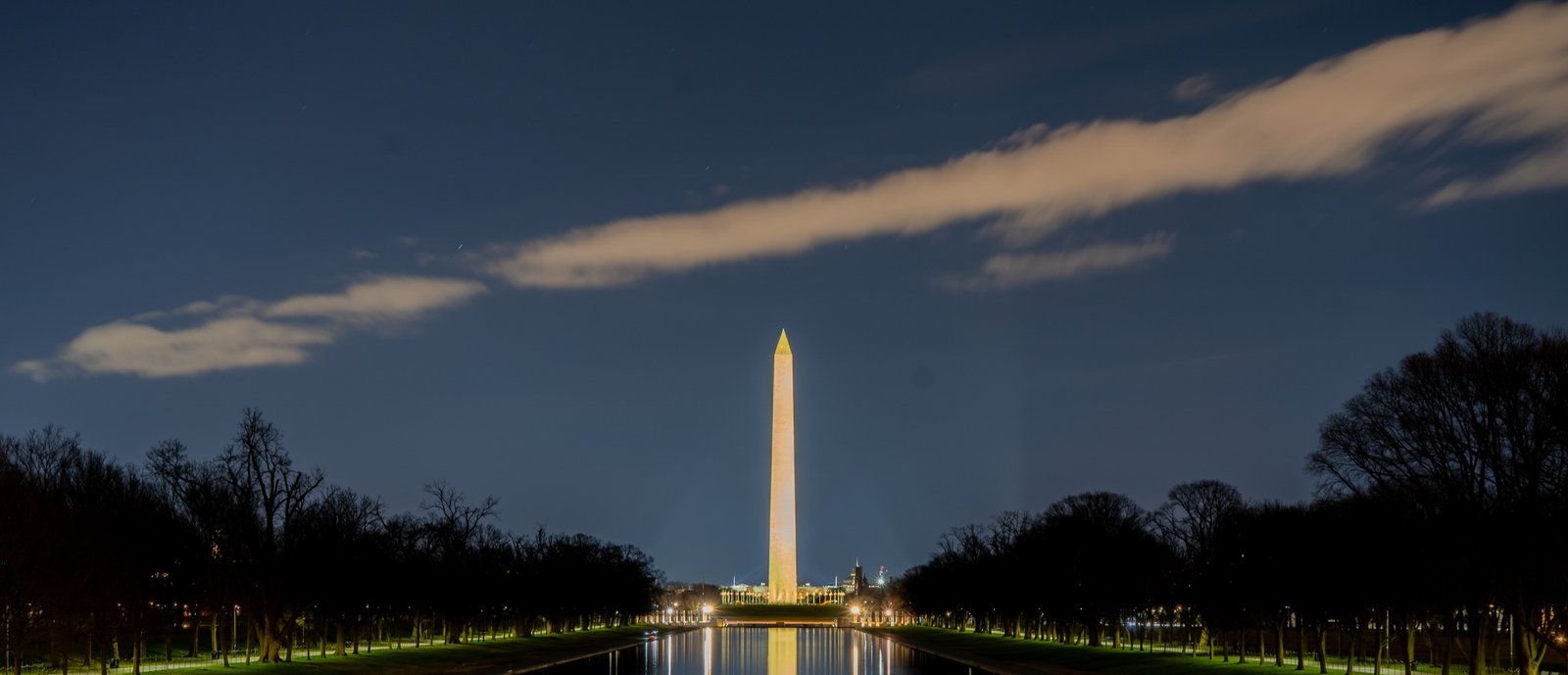 Washington Monument aligned with a dark reflecting pool at night