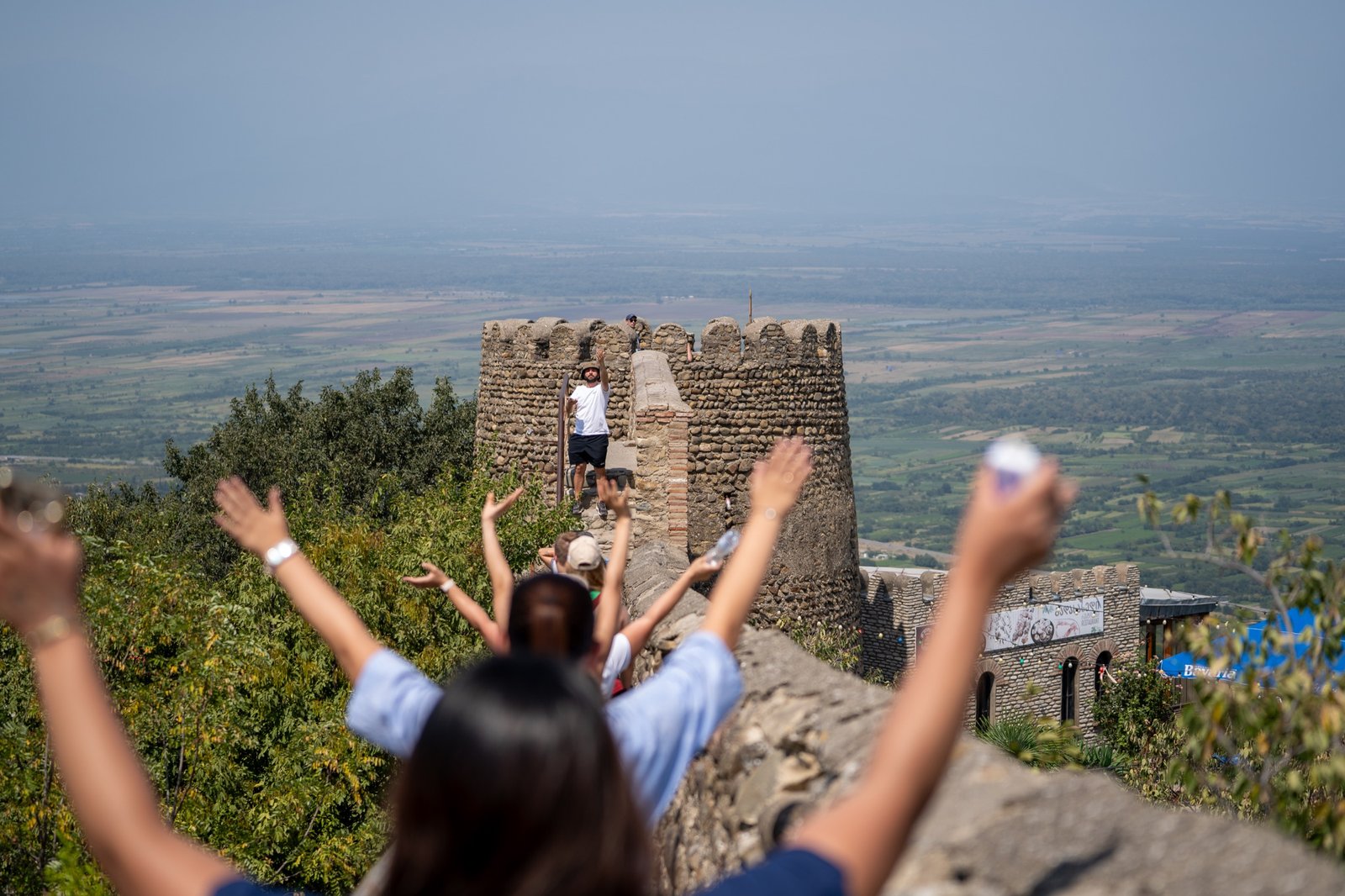 Traveler raising both arms at a mountain overlook above a wide valley