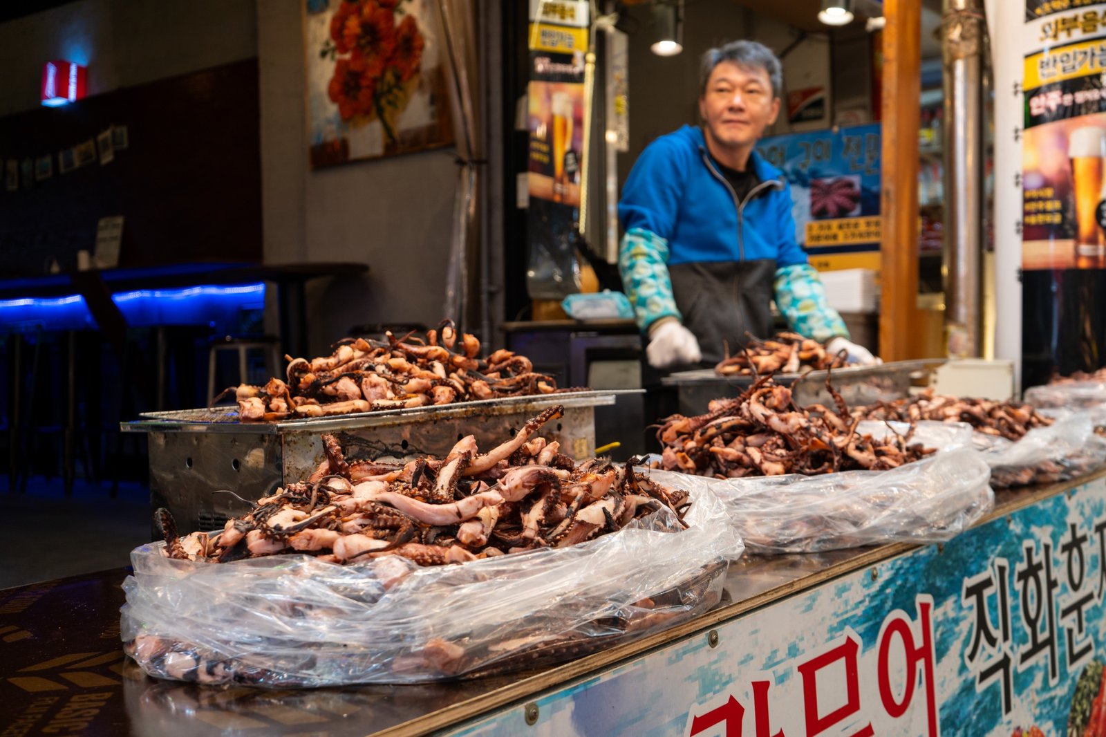 Seafood market stall with vendor behind rows of prepared squid