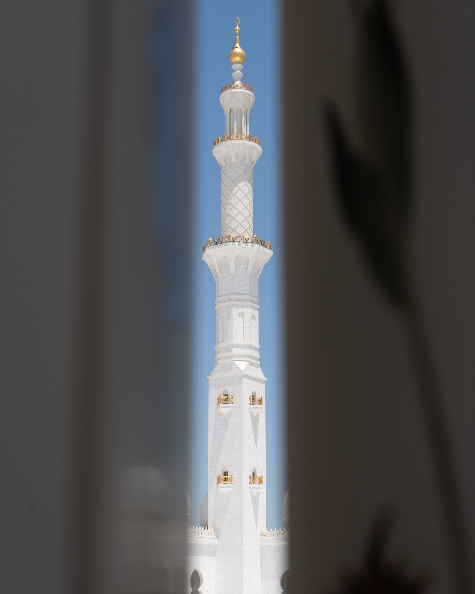 Tall white minaret seen through a narrow foreground opening